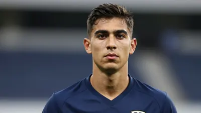 Photorealistic head-and-shoulders shot of a 25-year-old athletic winger with dark hair, wearing a solid navy blue jersey...