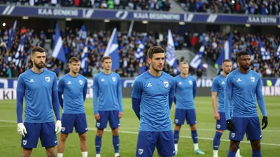 A photo of the KAA Gent players during the warm-up before the match, with the stadium in the background, showing a packed...