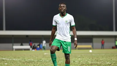 A 28-year-old Ivorian striker in a green and white jersey, with a white ball at his feet, looking up at the camera with a...