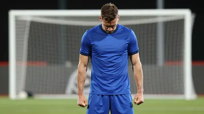 A frustrated Gent striker, mid-20s, muscular build, in a solid blue shirt, standing alone in the penalty area after a...
