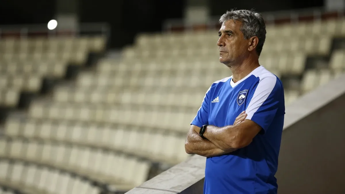 A 50-year-old, 5'10" Gent assistant coach, with a weathered face and graying temples, stands on the Planet Group Arena's...