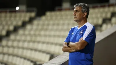 A 50-year-old, 5'10" Gent assistant coach, with a weathered face and graying temples, stands on the Planet Group Arena's...