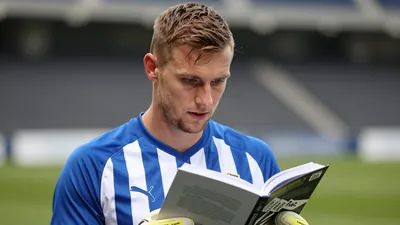 A photorealistic image of Gent goalkeeper Davy Roef, 32, looking at a book with information about the penalty takers of...