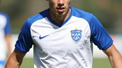A photo of a young, athletic player in action, wearing the KAA Gent jersey, with a blue and white color scheme and a mix...
